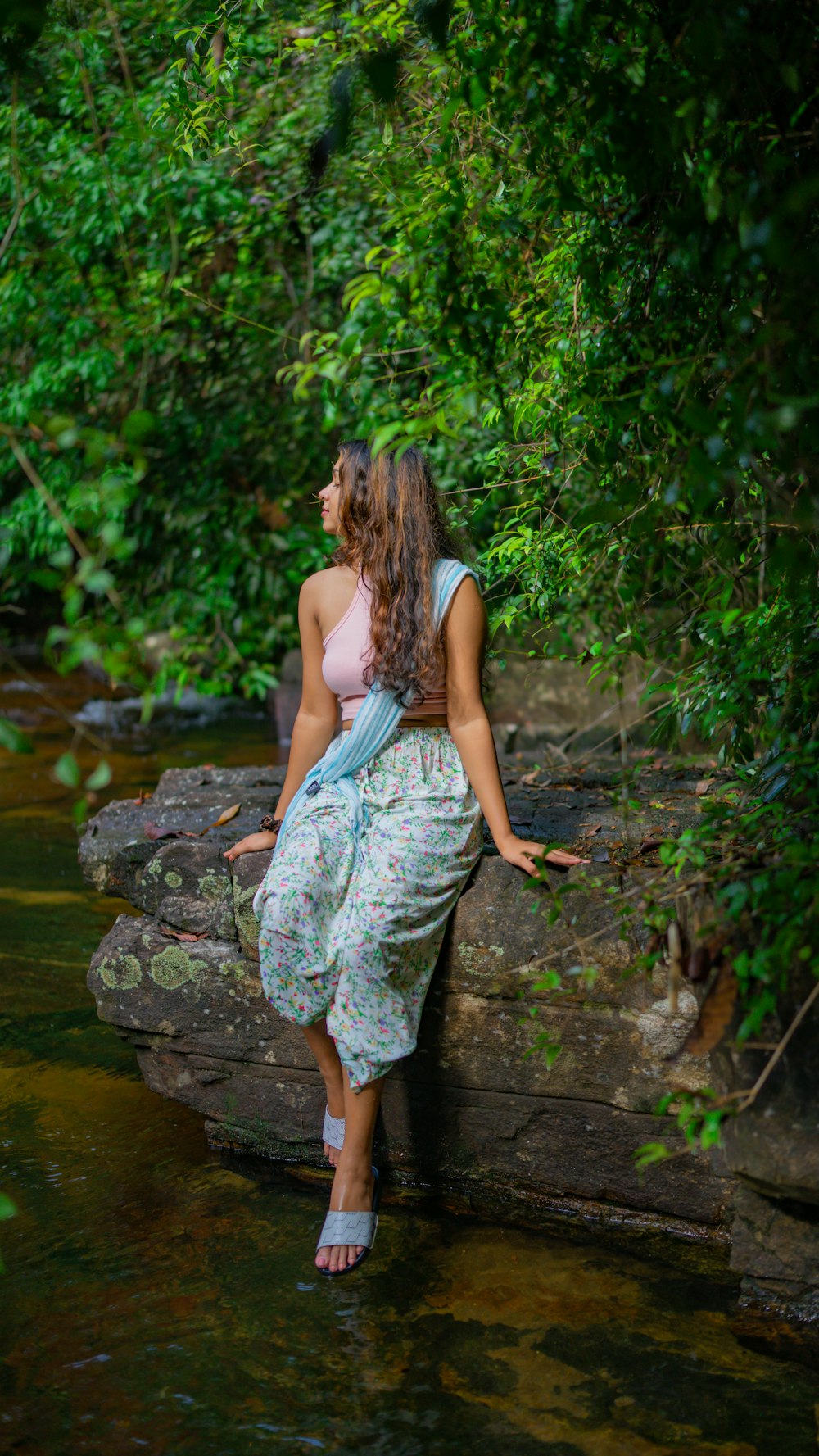 a woman sitting on a rock in the water