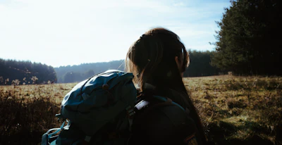 a woman standing in a field with a backpack on her back