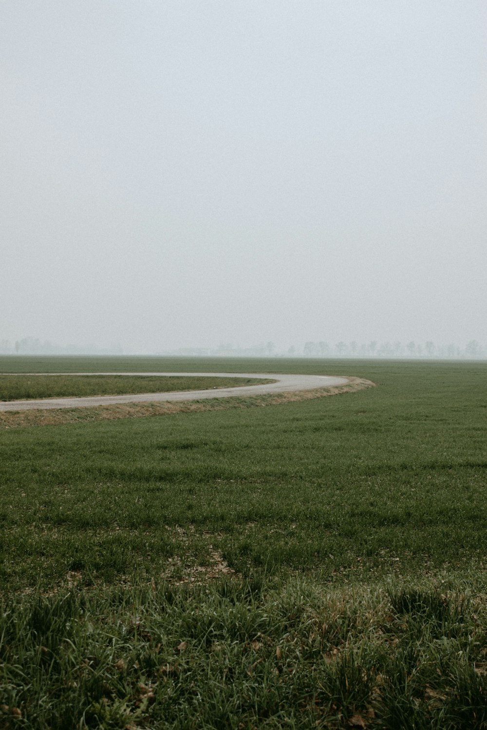 a field of grass with a road in the distance