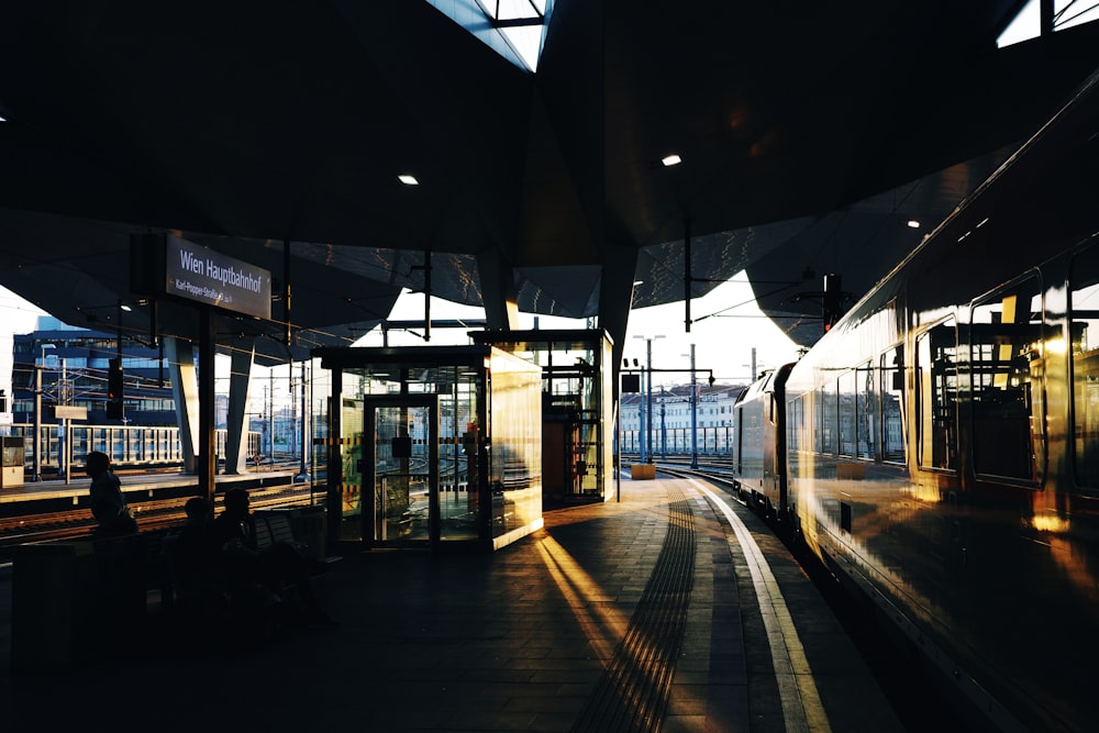 a train traveling past a train station next to tall buildings