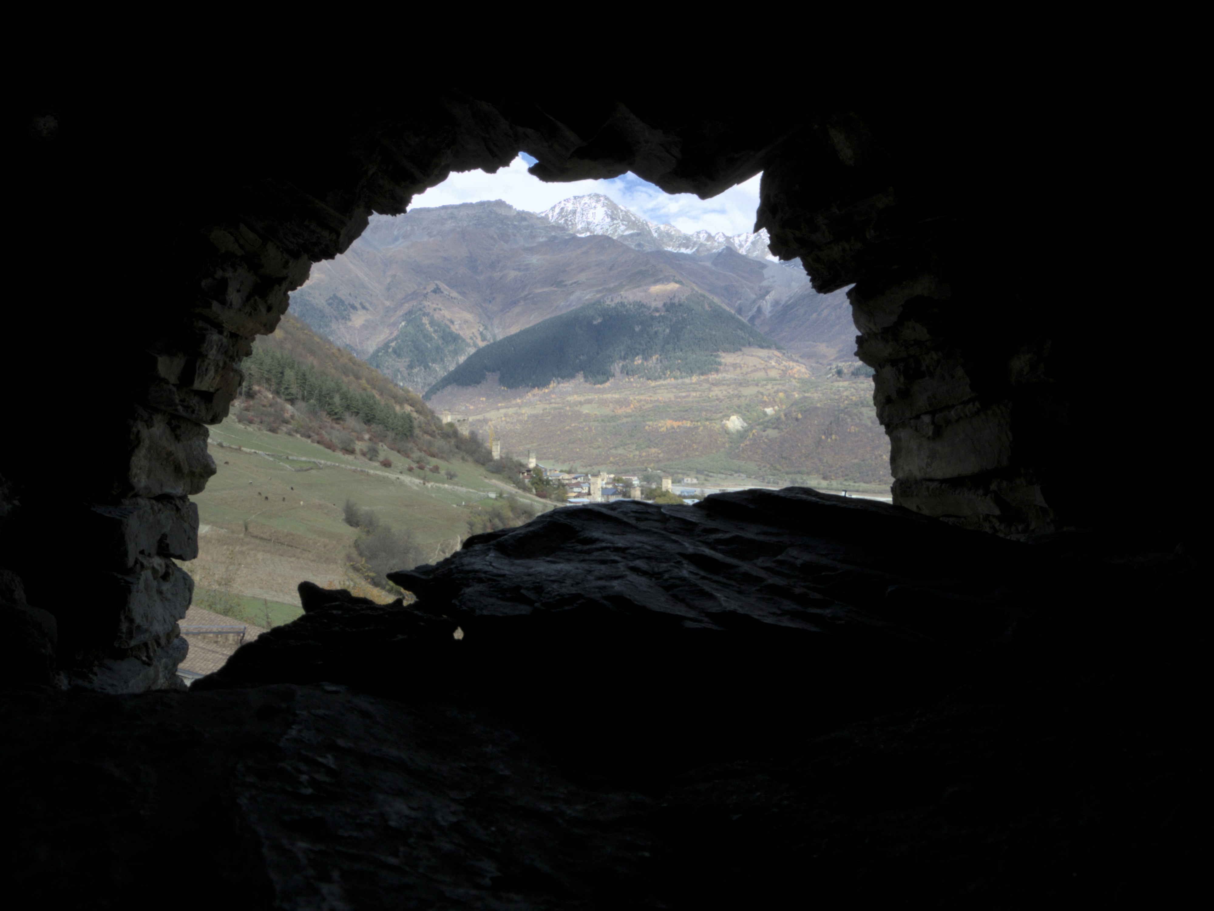 a view of a mountain range through a cave