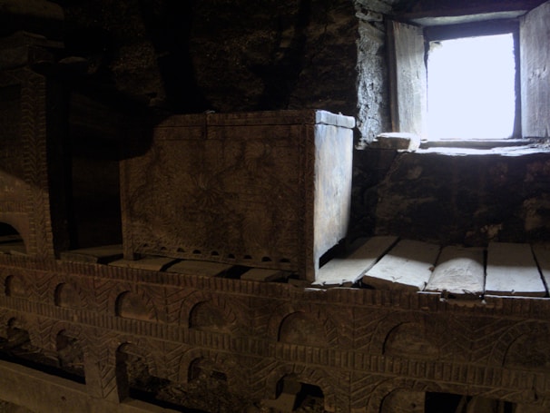 A finely carved wooden antique chest with intricate brass details, glowing softly under warm lighting.