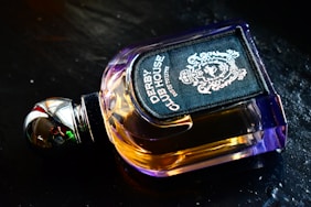 A sleek bottle of men's perfume with dark amber liquid and a minimalist label on a wooden surface.