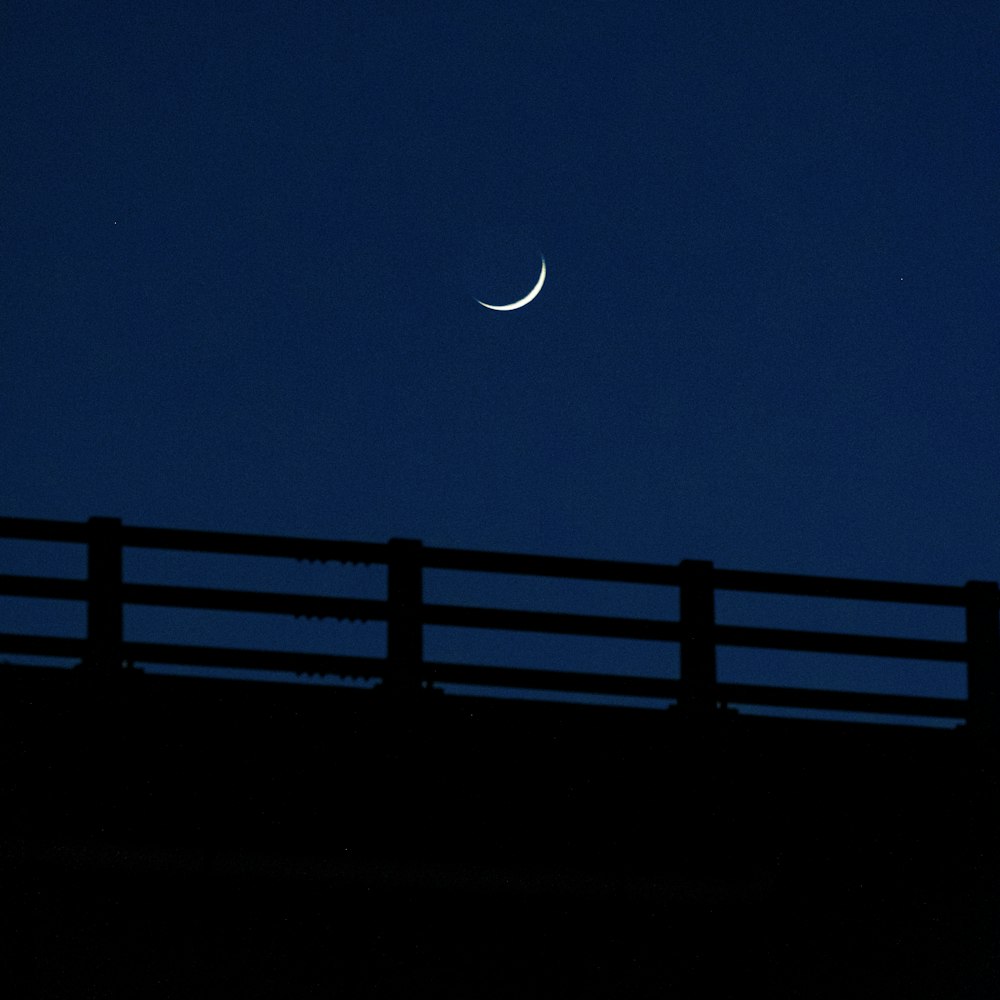 a half moon is seen in the sky over a bridge