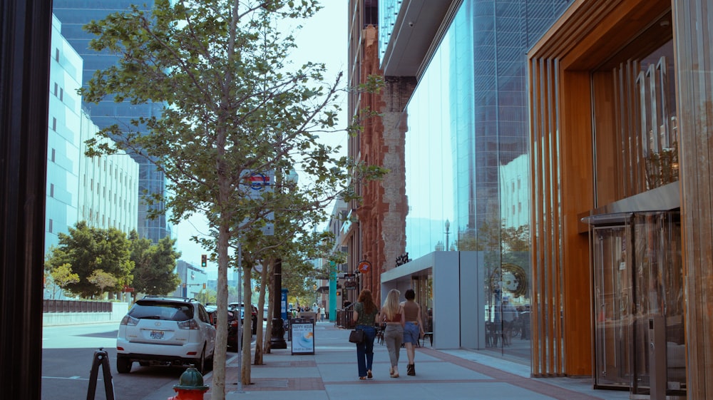 a couple of people walking down a sidewalk next to tall buildings