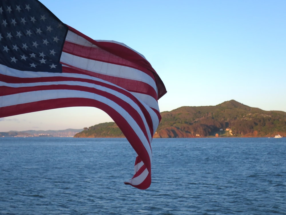 a large american flag flying over a body of water