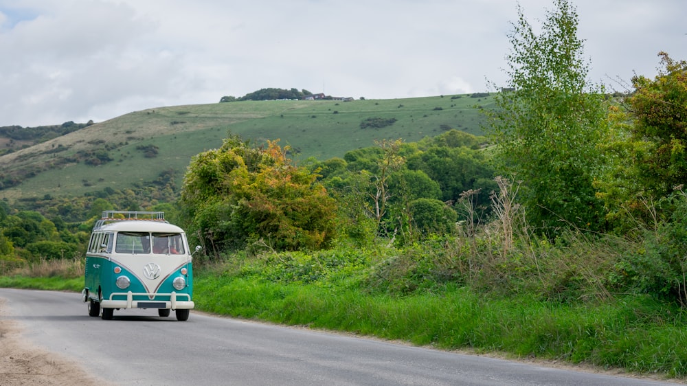 a blue and white bus driving down a rural road