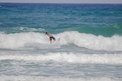 A surfer navigates through the crashing waves of the ocean, surrounded by frothy white water and deep blue sea. The scene conveys the energy and thrill of mastering the waves.