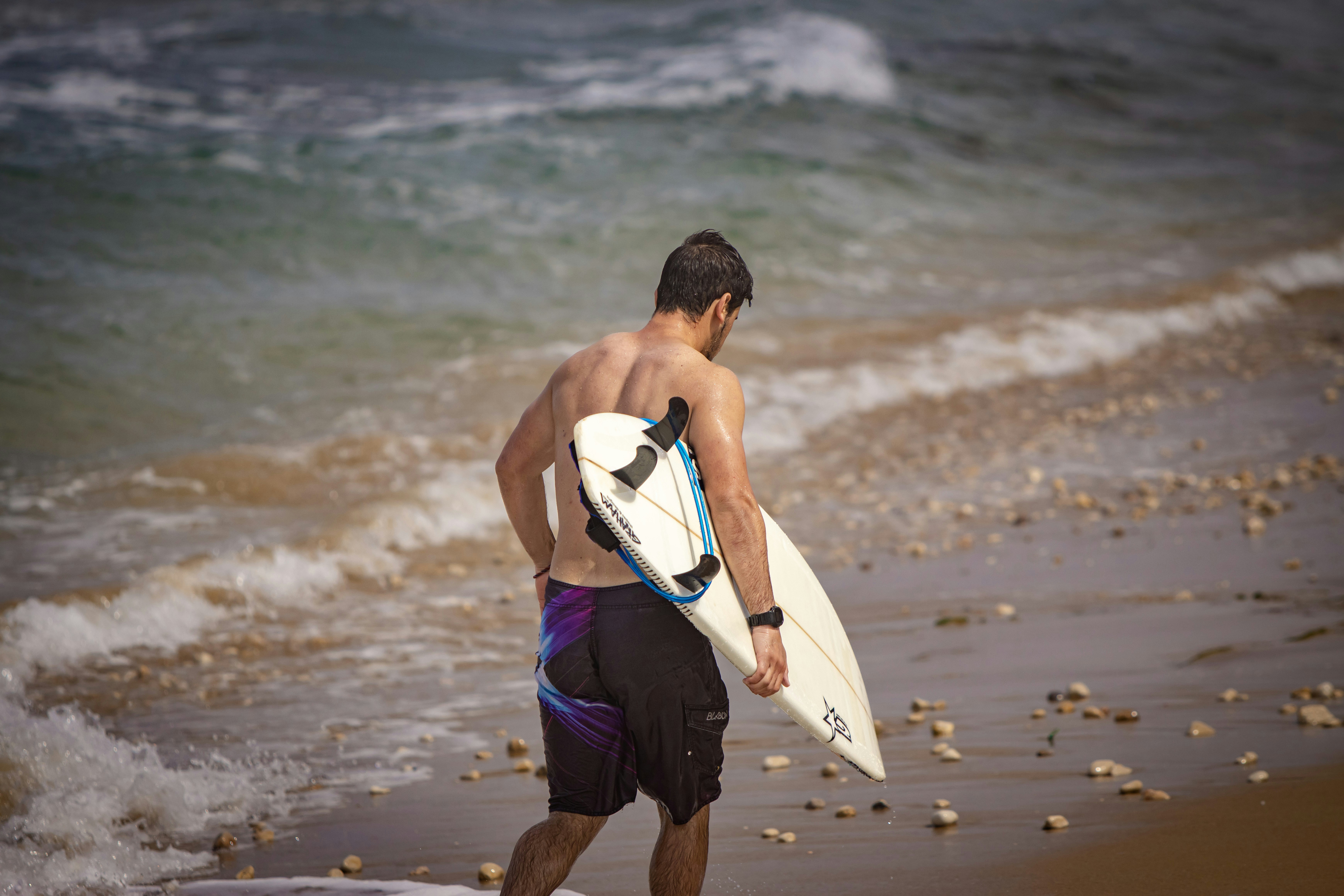 a man walking on the beach with a surfboard