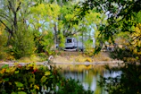 An outdoor recreational vehicle parked near a serene lake surrounded by pine trees.