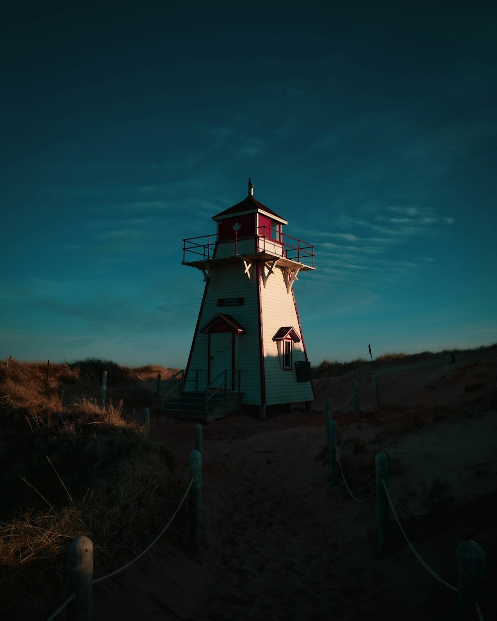 a white and red lighthouse sitting on top of a sandy beach