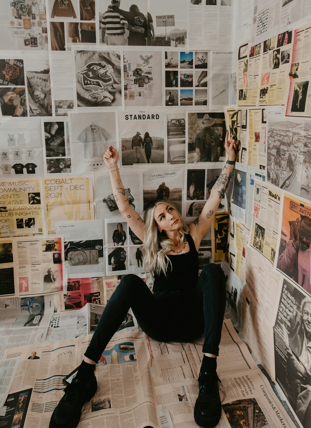 a woman sitting on top of a pile of newspapers