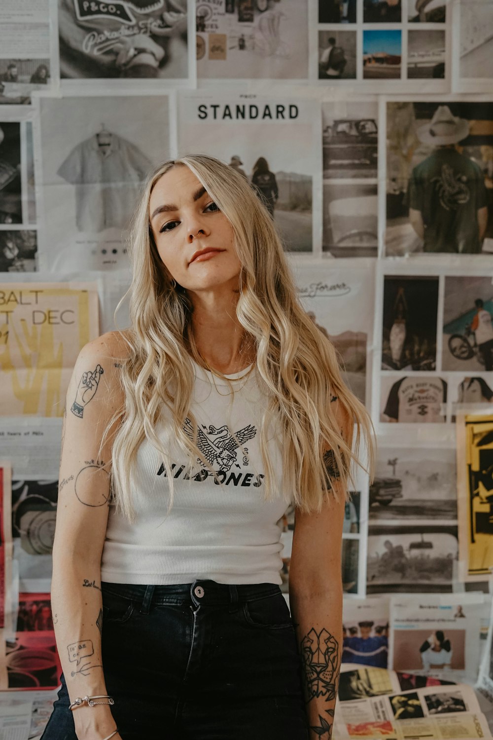 a woman with tattoos standing in front of a wall