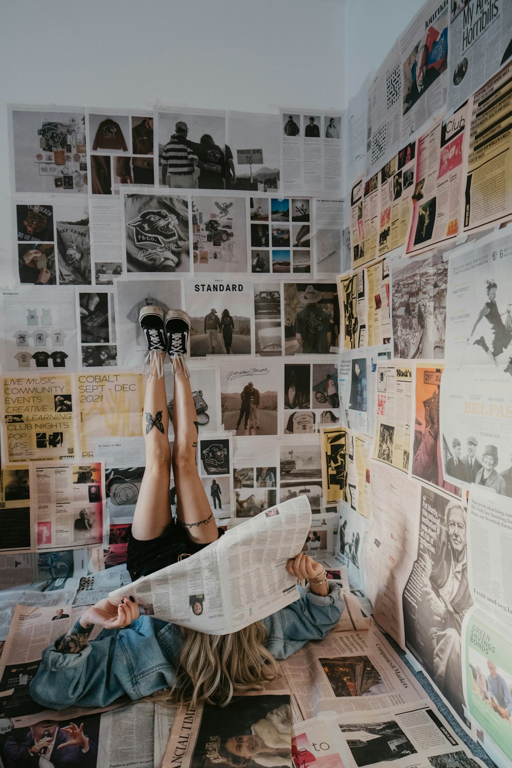 a woman laying on the floor reading a newspaper