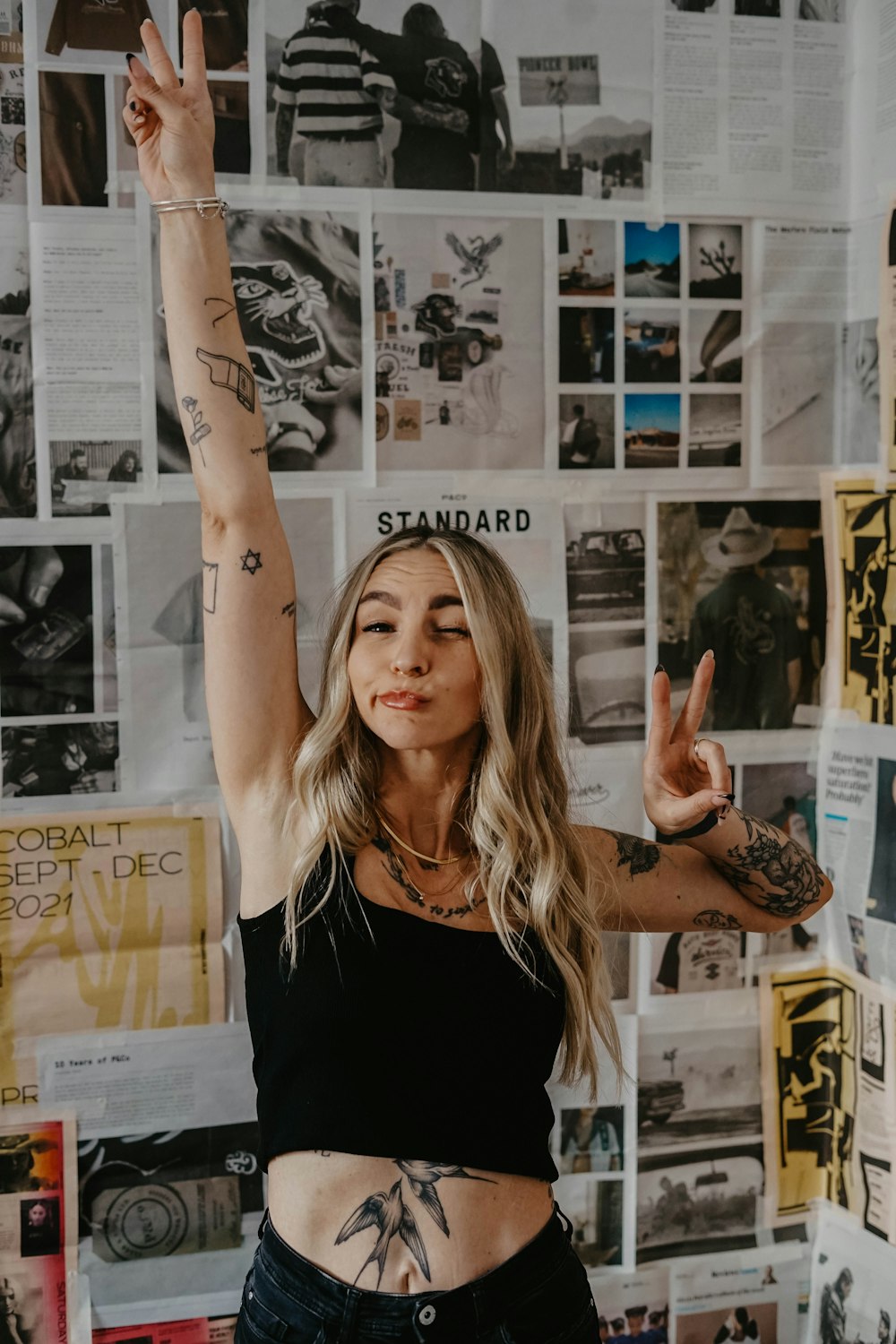 a woman standing in front of a wall covered in posters