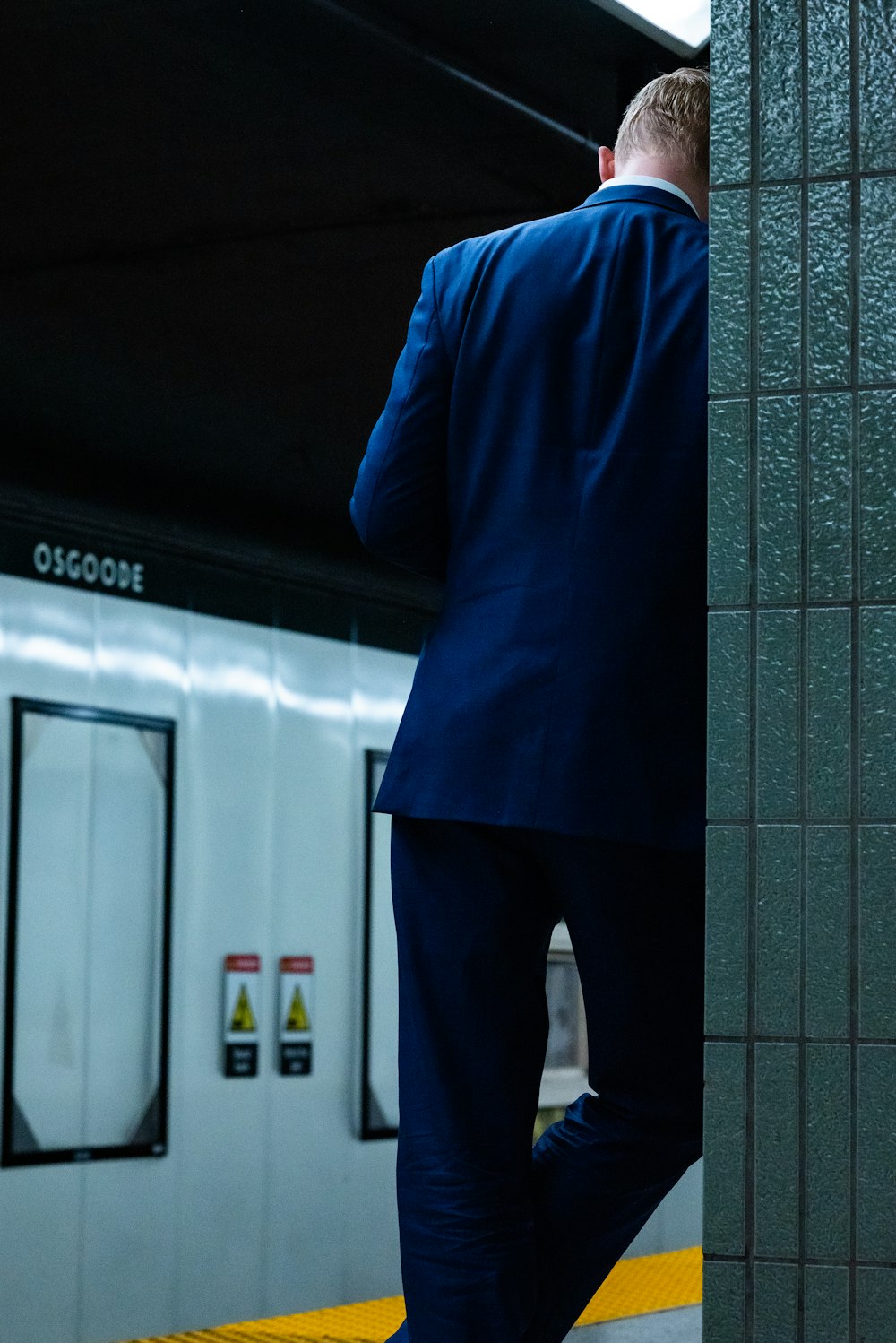 a man in a blue suit standing in a subway station