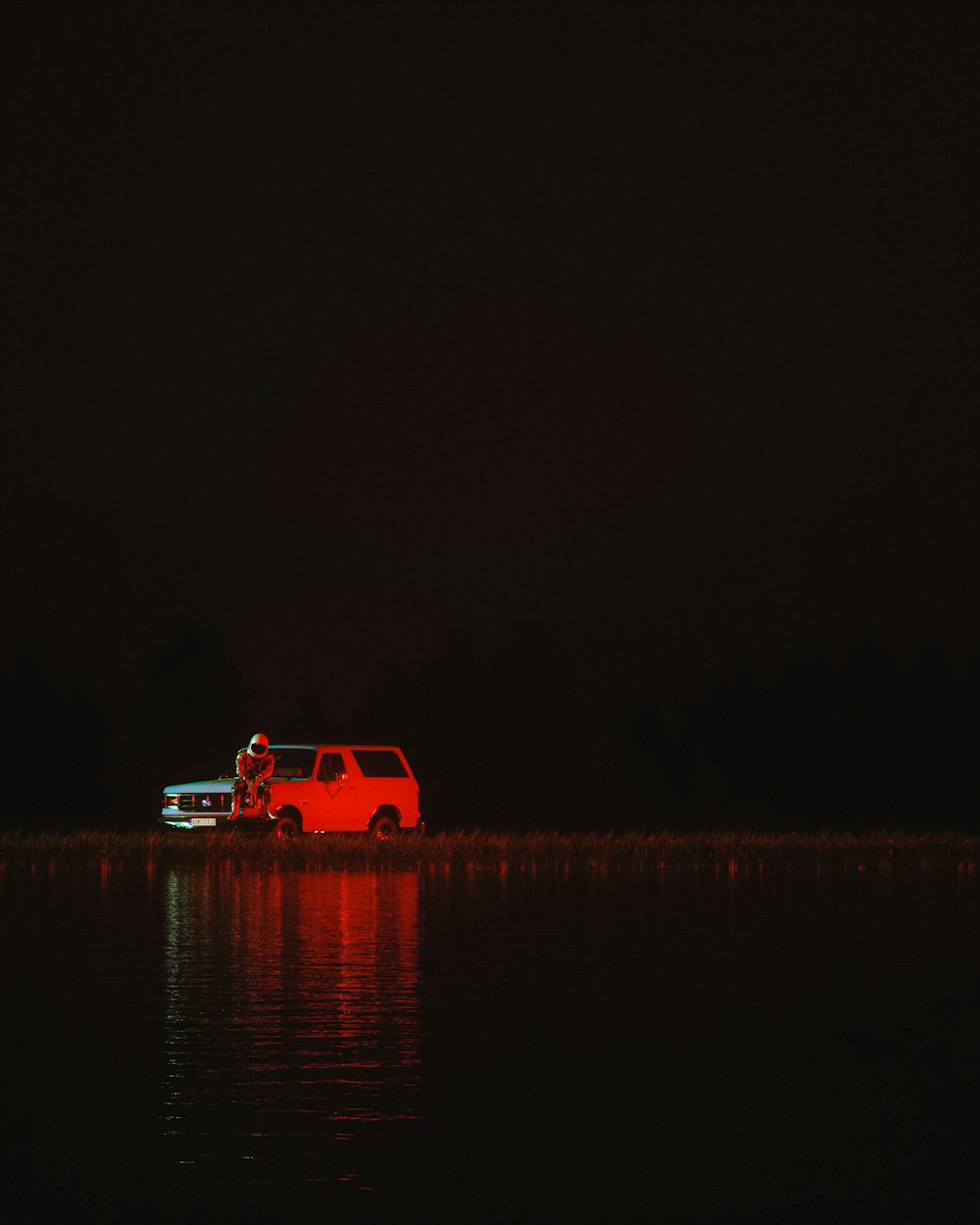 a red truck parked on top of a lake at night