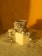 A stack of ornate silver bangles and jhumka earrings styled on a beige box, casting reflections and shadows on the soft fabric below, against a warm golden backdrop.