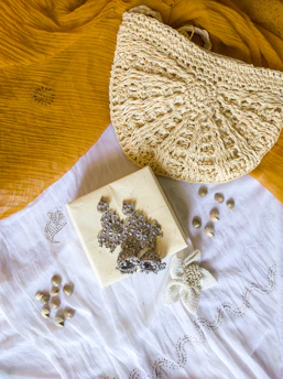 Close-up of a colorful embroidered fabric bag resting on a wooden table with sewing supplies scattered around.