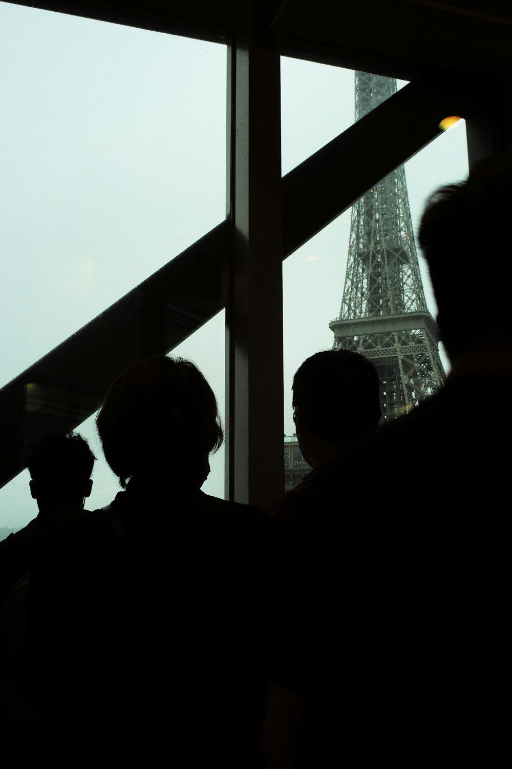 a group of people looking out a window at the eiffel tower