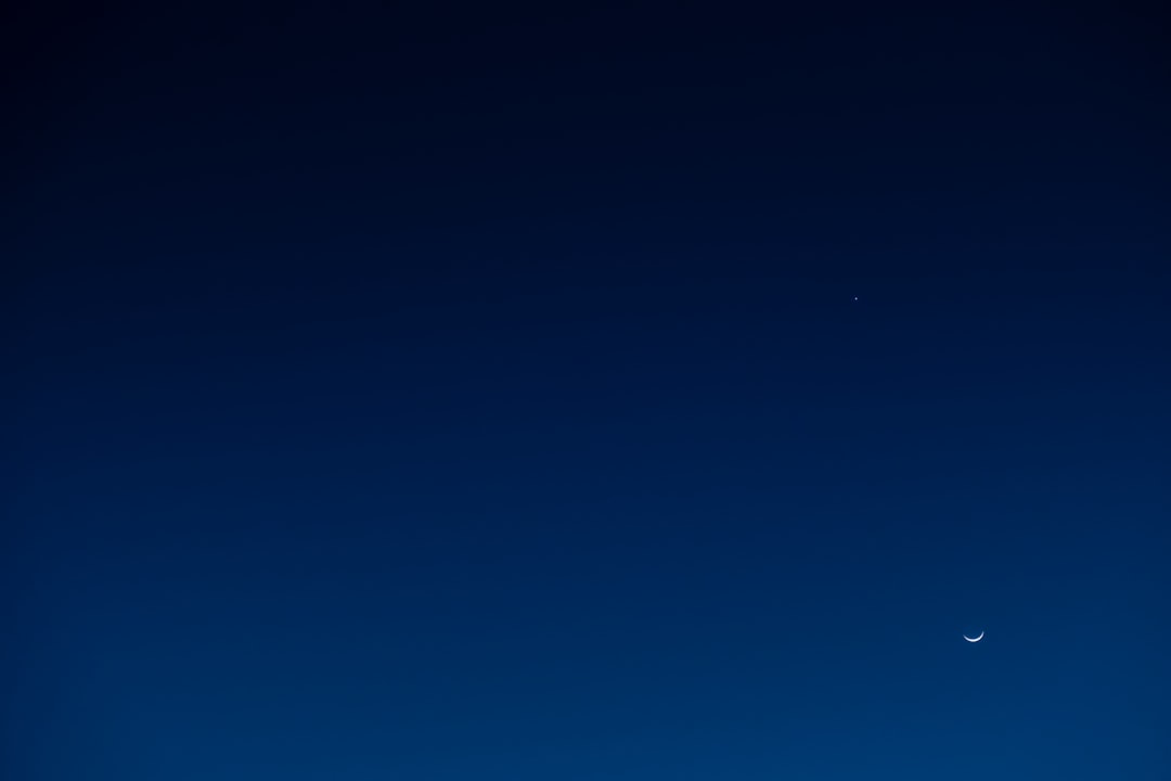 a plane flying in the sky with a moon in the background