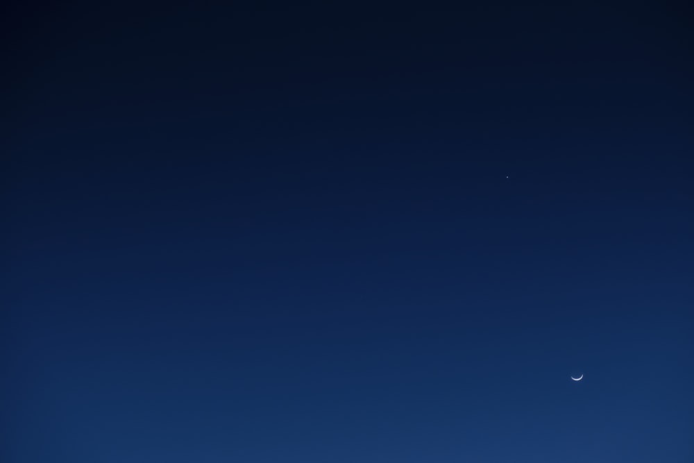 ein Flugzeug, das am Himmel fliegt, mit einem Mond im Hintergrund