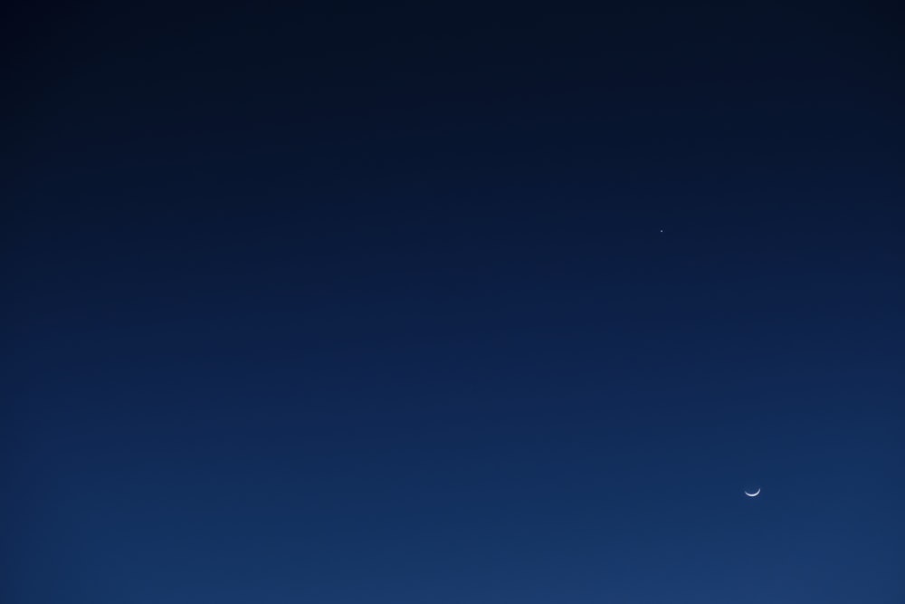 um avião voando no céu com uma lua ao fundo