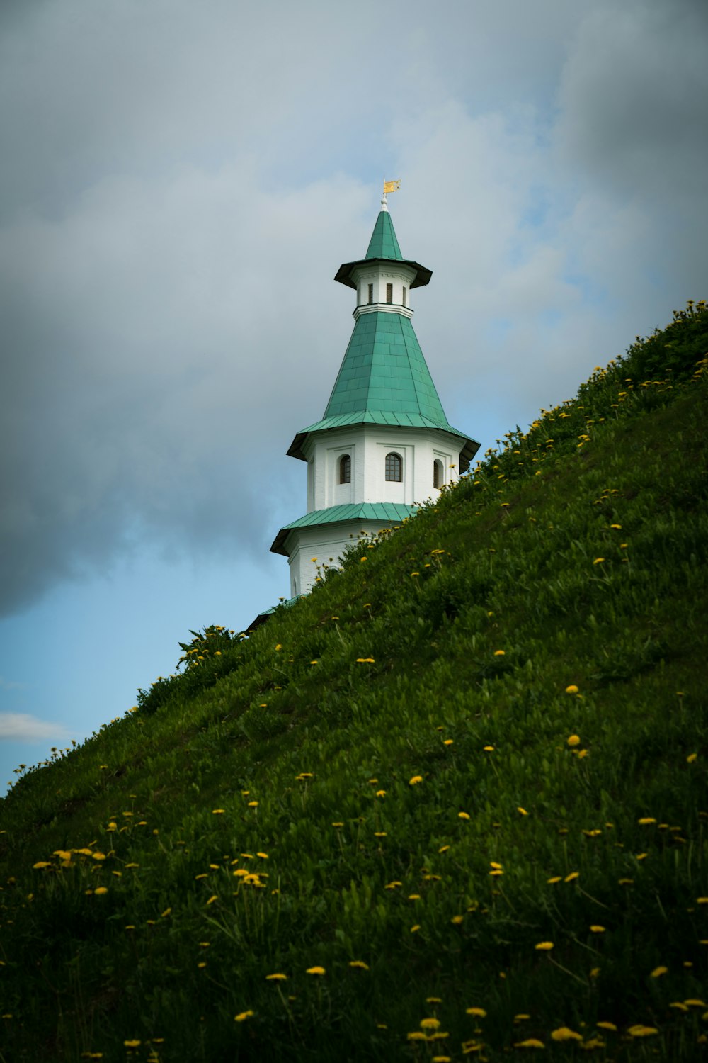 a white and green steeple on top of a hill