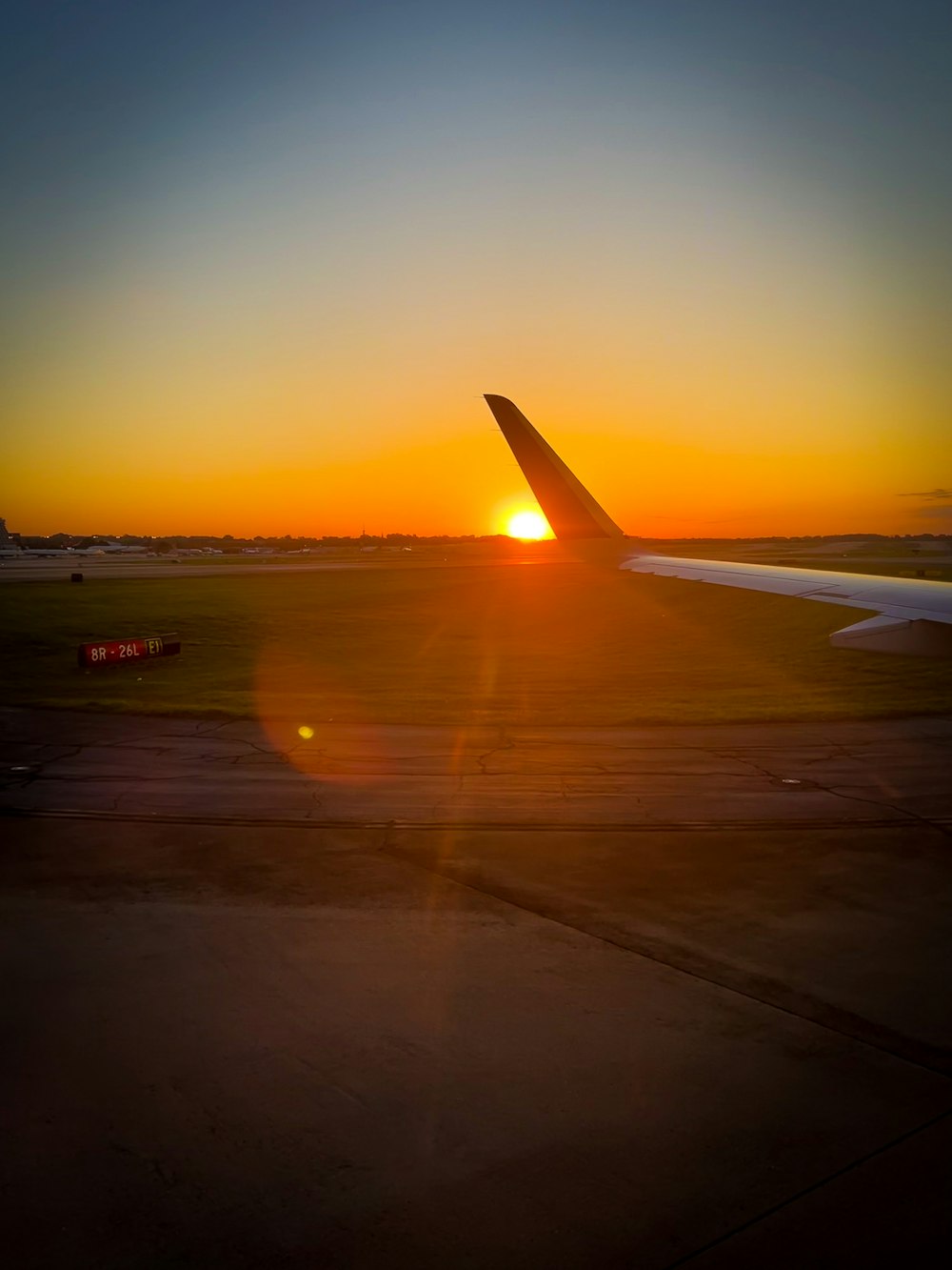 the sun is setting over the wing of an airplane