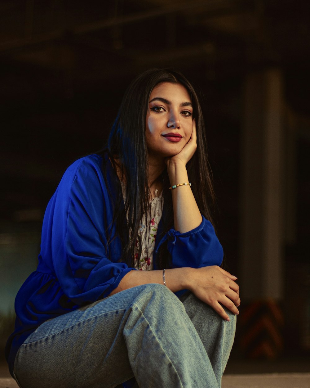 a woman sitting on the ground with her hand on her chin