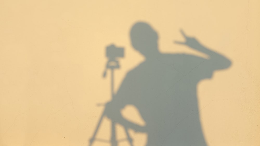 a shadow of a man standing next to a camera