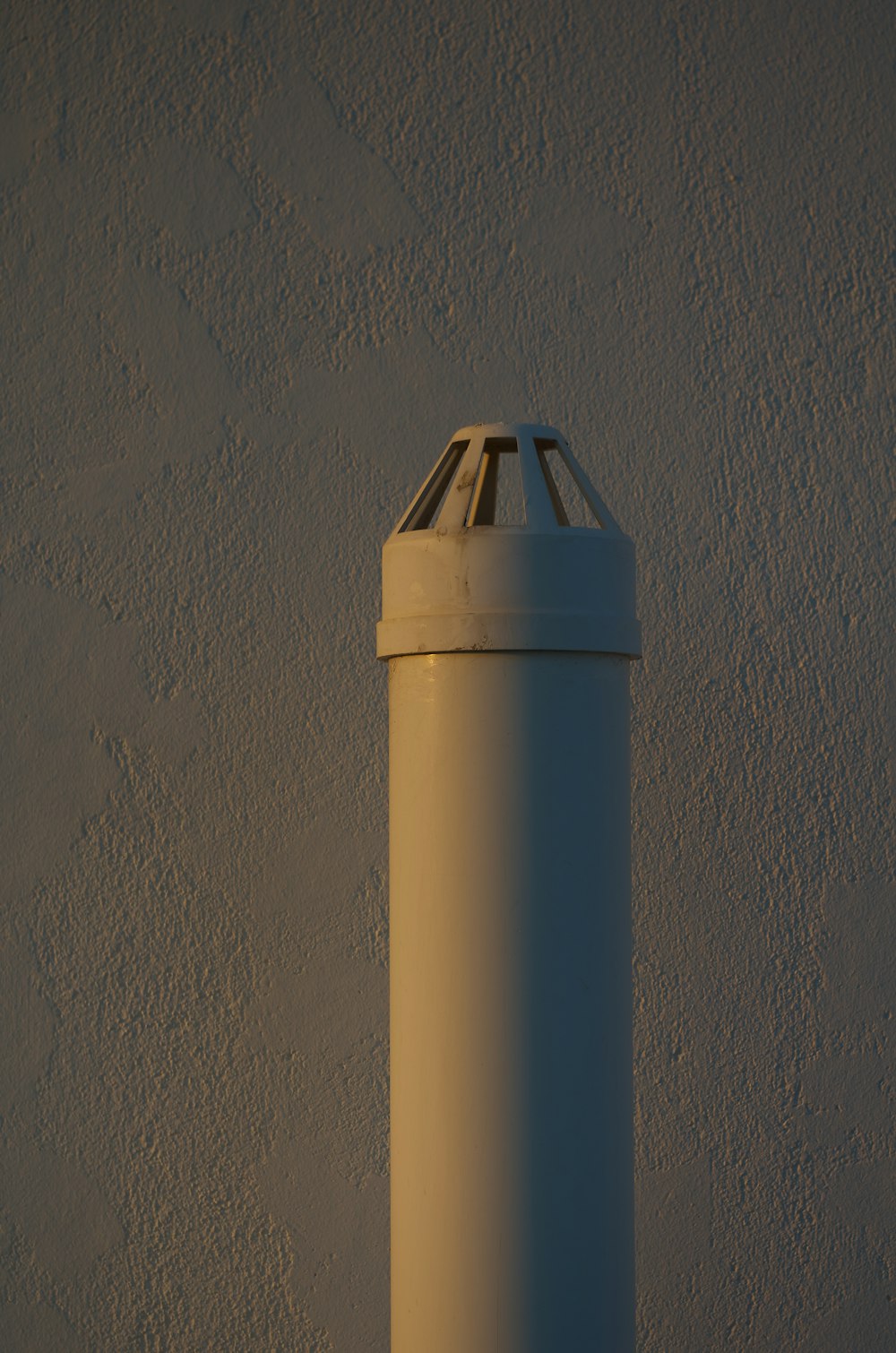 a tall white pole against a white wall