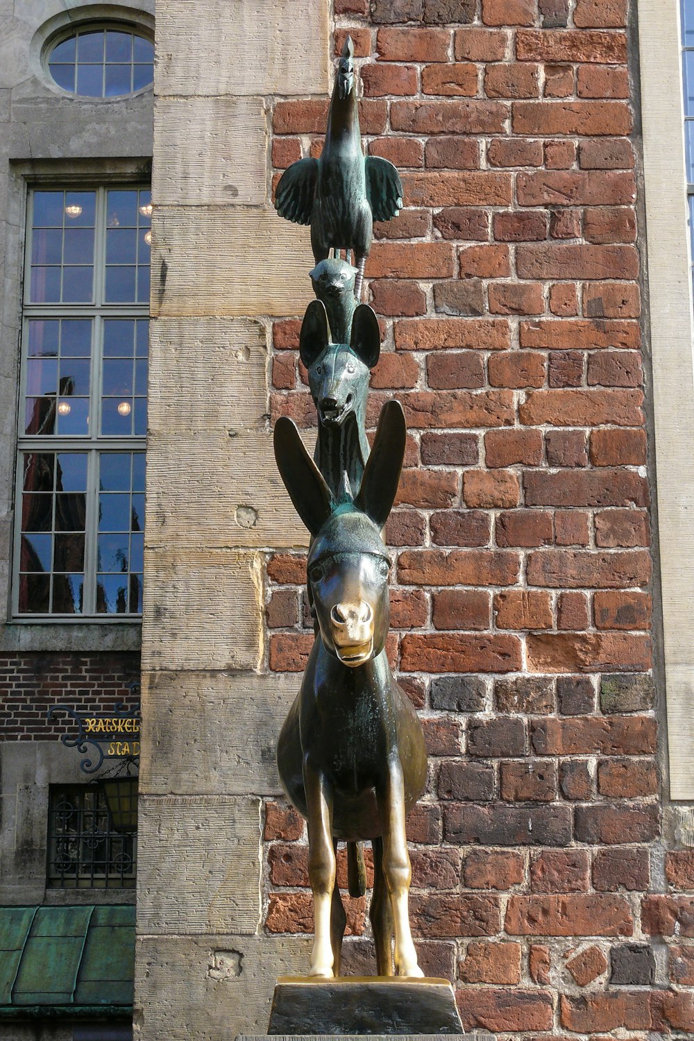 a statue of a dog and a bird on a brick wall