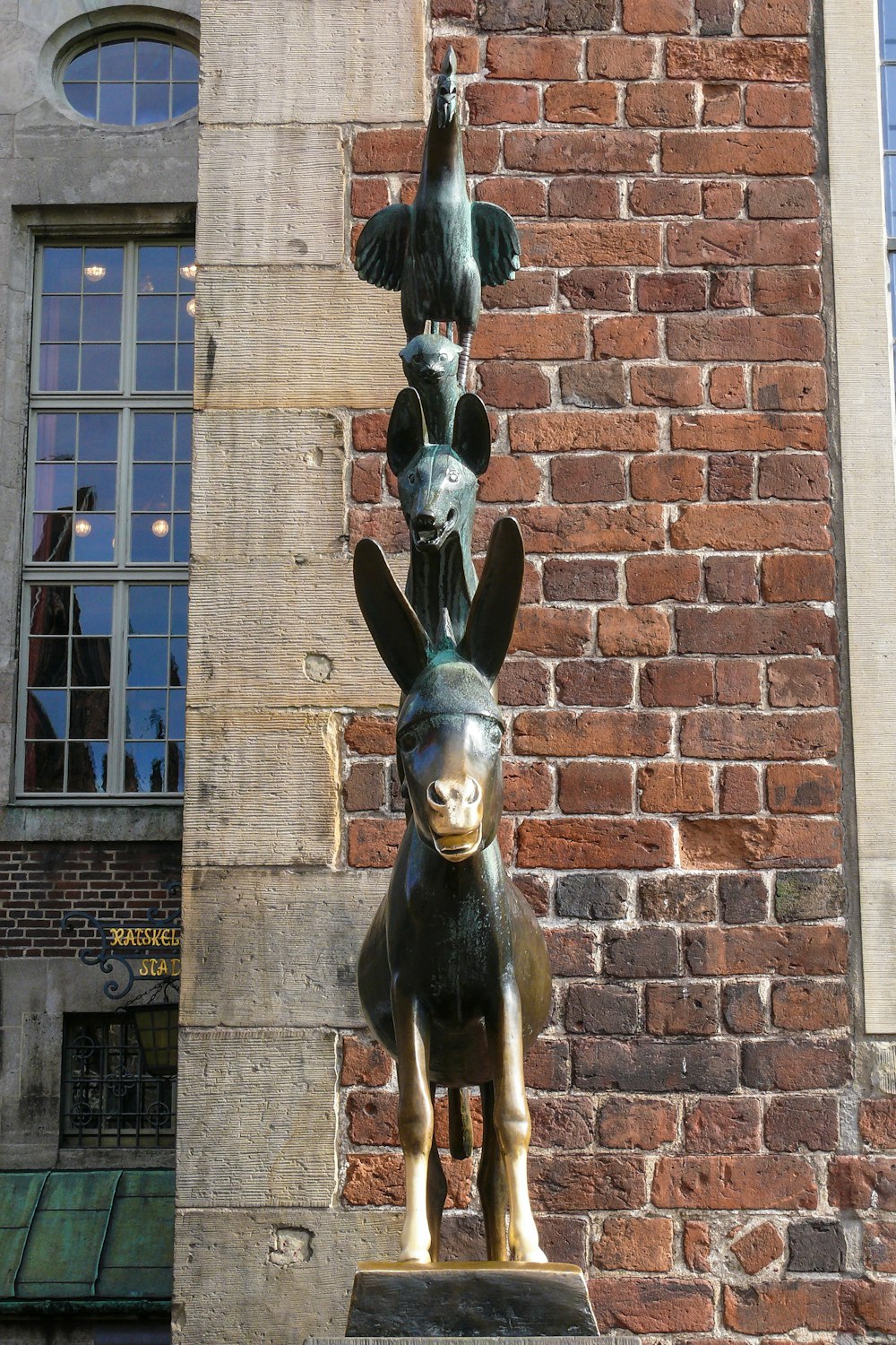 Una estatua de un perro y un pájaro en una pared de ladrillo