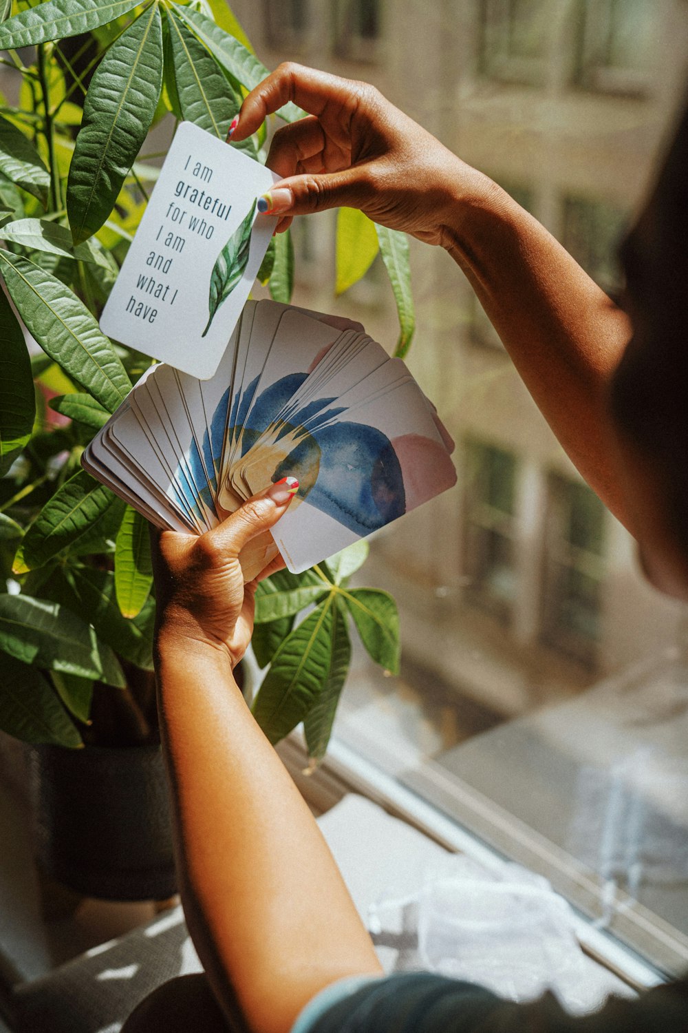 a person holding a card next to a potted plant