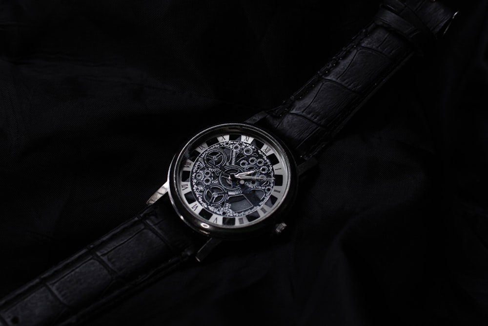 a watch with a black leather strap on a black background
