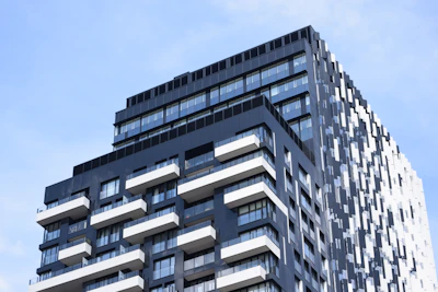 Sleek black and white high-rise building with red trim against a clear blue sky.