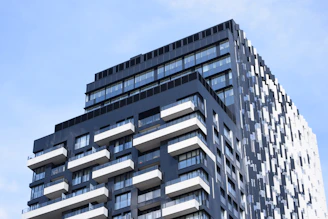 Sleek black and white high-rise building with red trim against a clear blue sky.