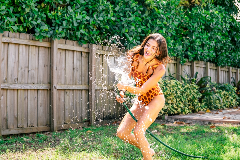 Una mujer con un traje de baño con estampado de leopardo rociando agua sobre su cuerpo