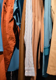 a bunch of different colored shirts hanging on a rack