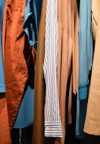 a bunch of different colored shirts hanging on a rack