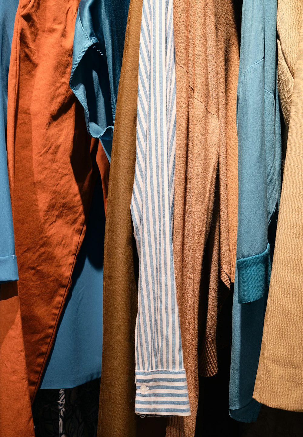 a bunch of different colored shirts hanging on a rack