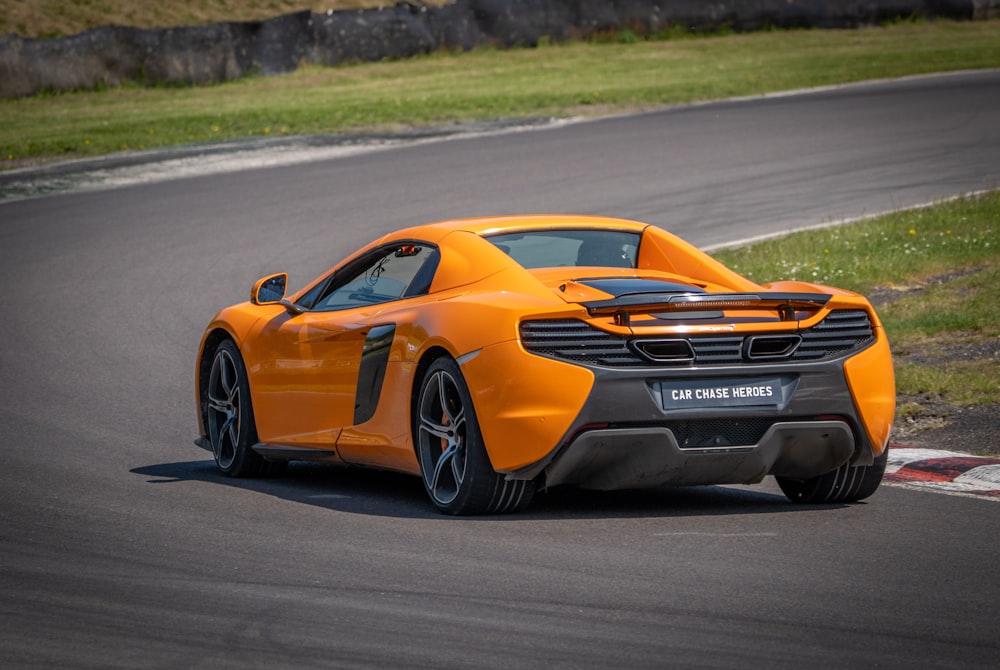 Un'auto sportiva arancione che guida su una pista da corsa