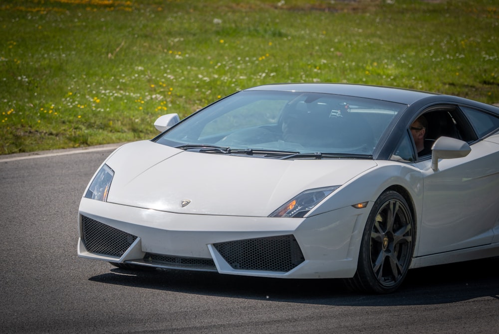 a white sports car driving down a road