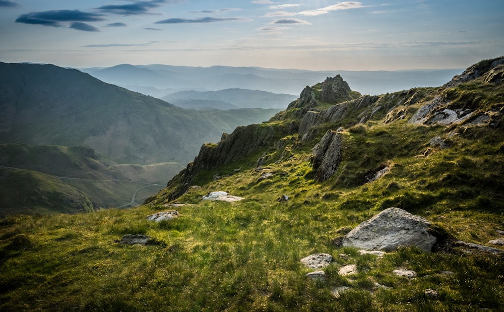 a view of a mountain range with a grassy field in the foreground