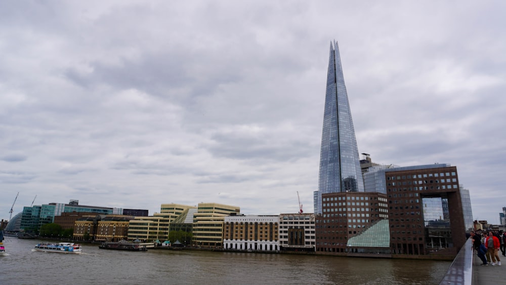 a group of people walking along a river next to a tall building