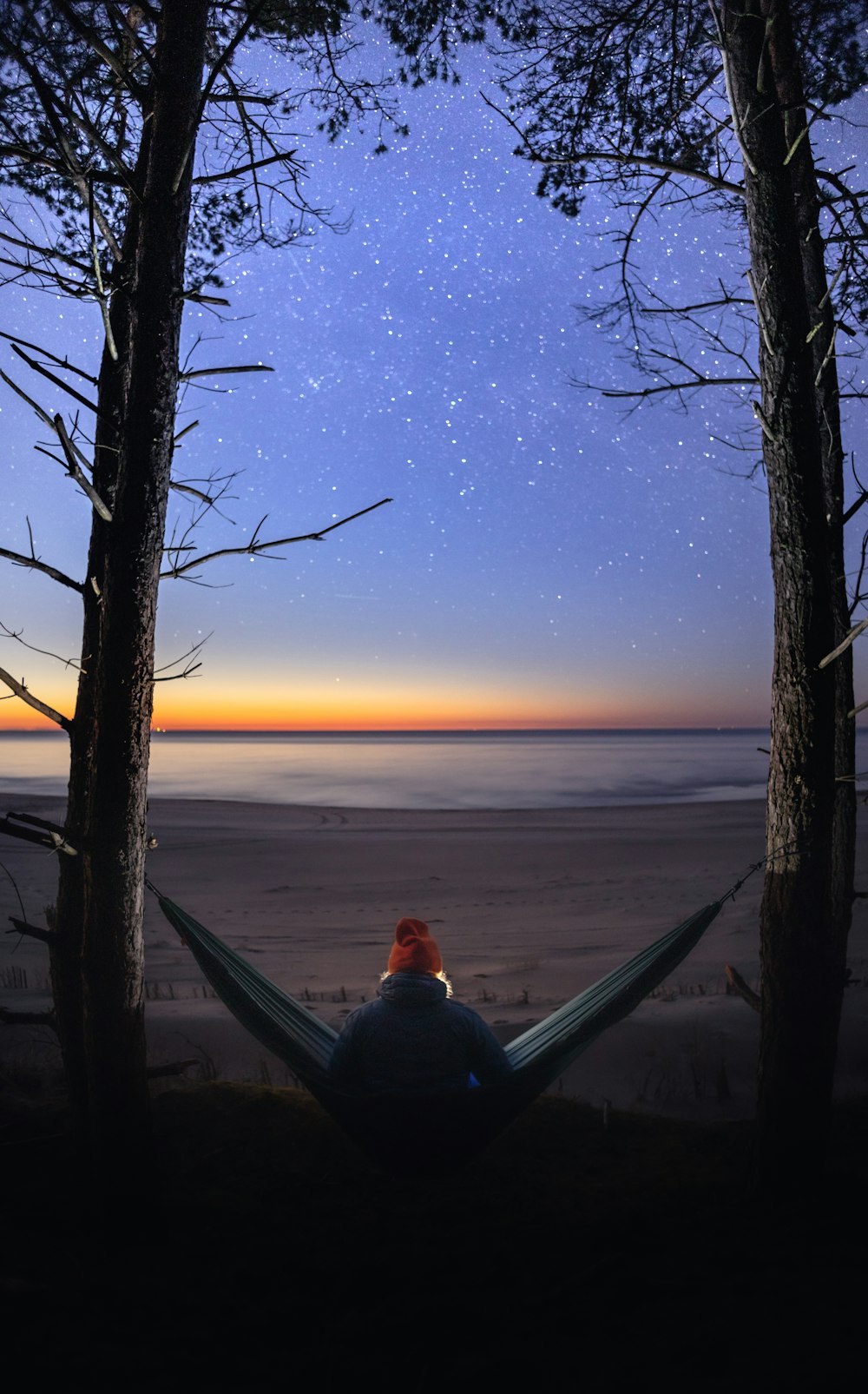 a person sitting in a hammock on a beach