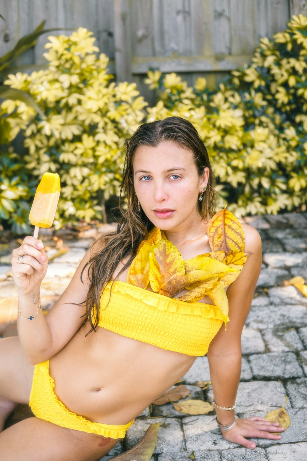 a woman in a yellow bikini holding a banana