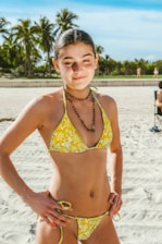 A vibrant bikini set laid out on a sandy beach with seashells around.