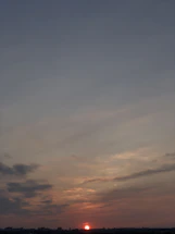 A warm beige and brown sunset casting soft rays over a calm horizon.